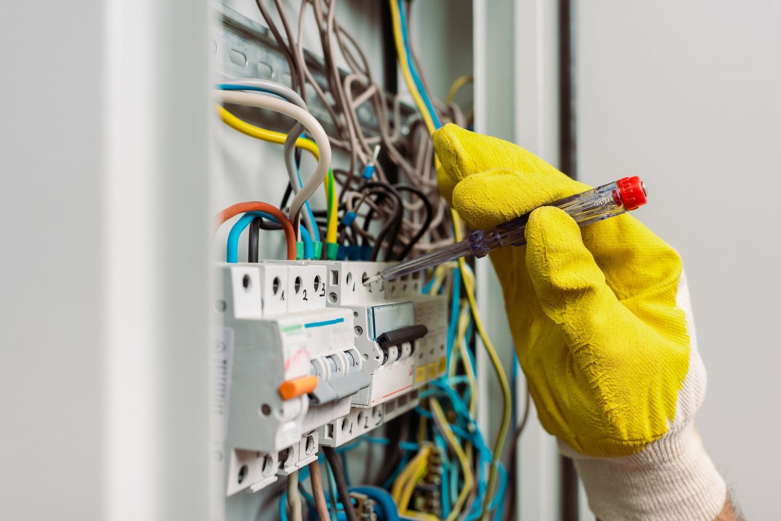 A qualified electrician working inside a residential distribution board.