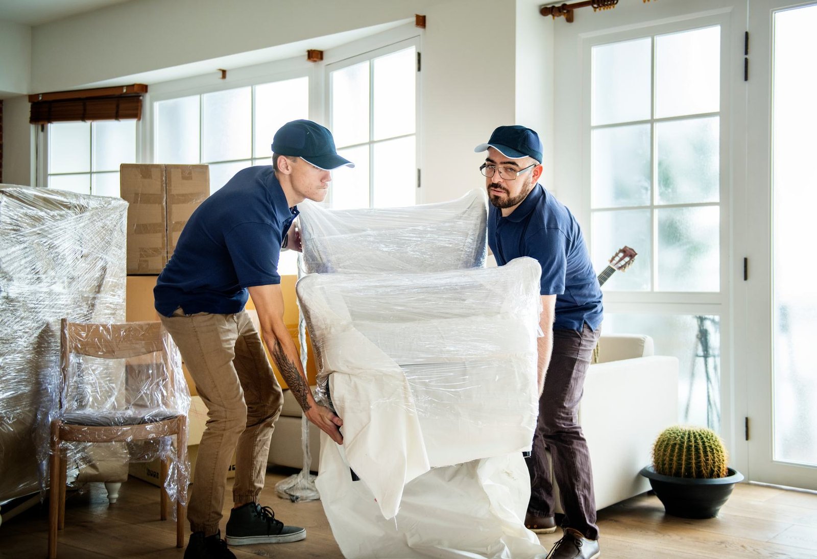 Two service professionals wrapping furniture inside a home
